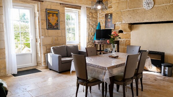 A dining area with a table set for four, a sofa, a television, and a fireplace.