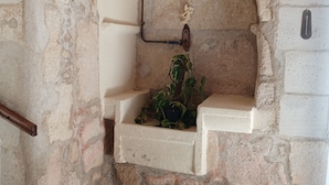A stone wall with a built-in shelf, a pipe, and a thermometer.