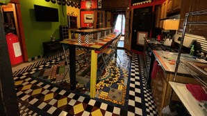 Restaurante com chão quadriculado, balcão comprido e ventilador de teto.