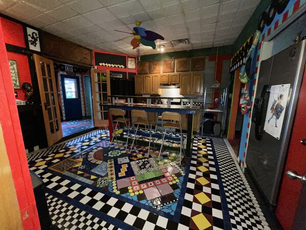 A kitchen with a checkered floor, wooden cabinets, a bar area, and a refrigerator with a poster.