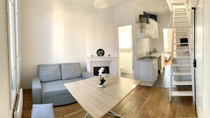 Een moderne woonkamer met een grijze bank, een houten salontafel en een witte open haard.