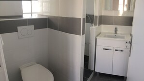 Een moderne badkamer met toilet, douche en wastafel.