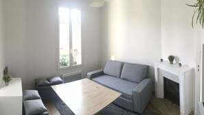 Een moderne woonkamer met een grijze bank, een houten salontafel en een open haard.