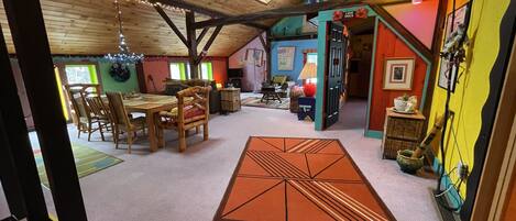 Cozy multi-level space with a dining area, wooden table, and colorful rug.