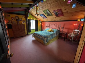 Une chambre à coucher avec un lit, une commode, une chaise et une fenêtre.