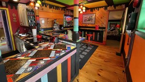 Een levendige bar met een kleurrijk geborduurde bar en houten details, en diverse barstoelen.