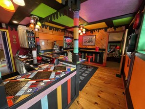 Un espace bar animé, avec un comptoir coloré à motifs matelassés, des éléments décoratifs en bois et une variété de tabourets de bar.