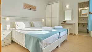A modern bedroom with a large bed, bedside tables, a desk, a mirror, and a bathroom with a shower. - Beachside Bungalow 3 Acharavi Corfu (Αχαράβη)