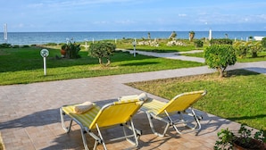 A patio area with two yellow lounge chairs and a pathway leading to the beach. - Beachside Bungalow 3 Acharavi Corfu (Αχαράβη)
