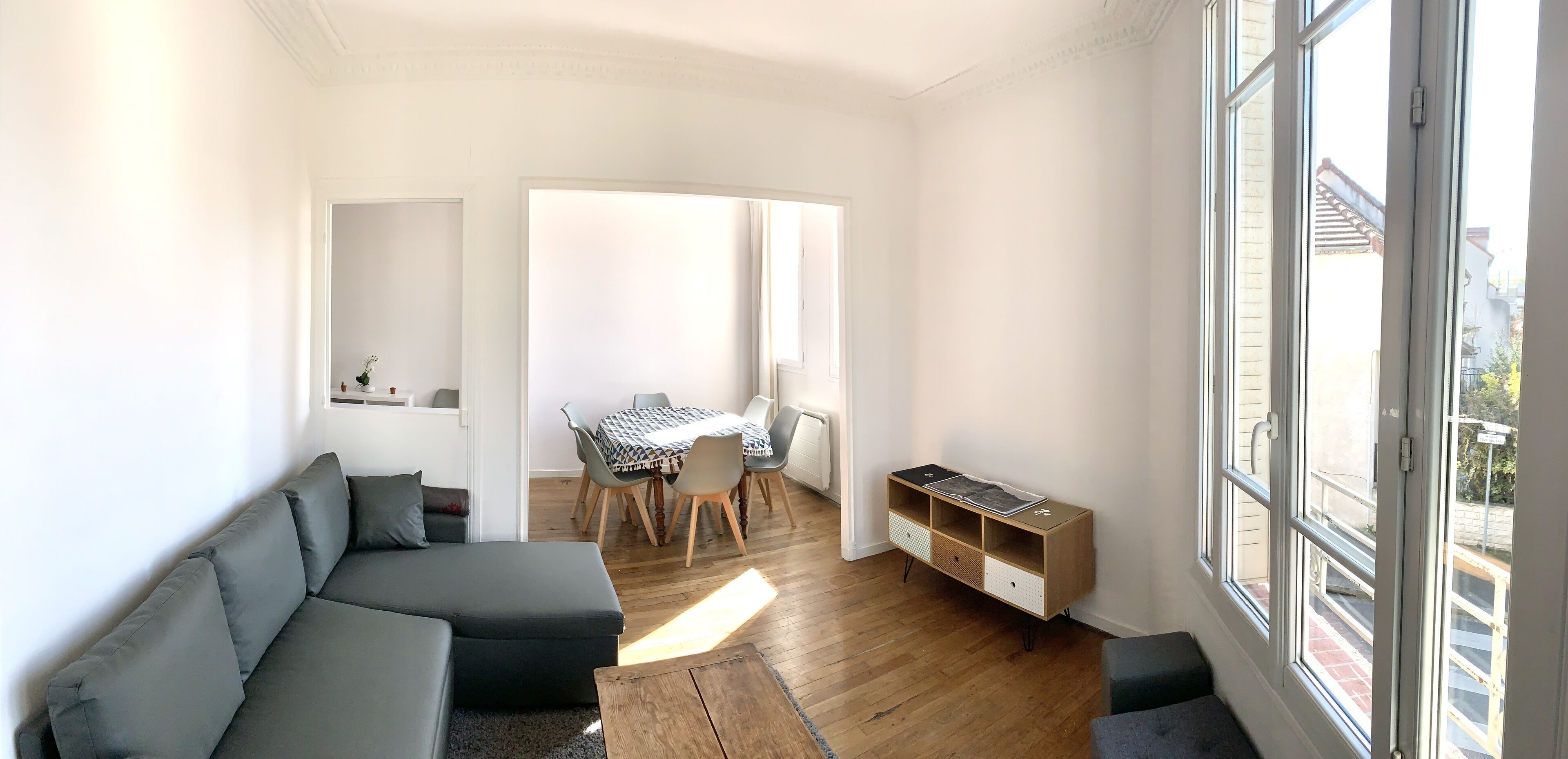 A modern living room with a sofa, dining table, and a wooden cabinet.