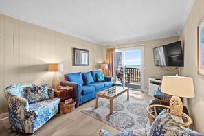 Relax in this inviting living room with a sofa, armchair, and coffee table, perfect for unwinding with a view of the outdoors.