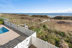 Enjoy ocean views from this beachfront property, featuring a pool and a fence.