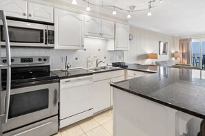 Enjoy cooking in this well-equipped kitchen with stainless steel appliances, white cabinetry, and a large island.