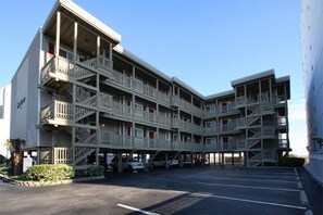 Un hôtel à plusieurs étages, doté de balcons et d’un espace de stationnement.