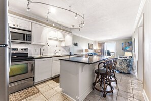 Een moderne keuken met witte kastjes, roestvrijstalen apparatuur en een centraal eiland met barkrukken.