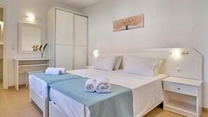 Ein Hotelzimmer mit zwei Betten, einem Schreibtisch, einem Kleiderschrank und einem Bild an der Wand.