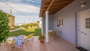 Eine überdachte Terrasse mit Sitzgelegenheit, einer Tür und einer Fußmatte.