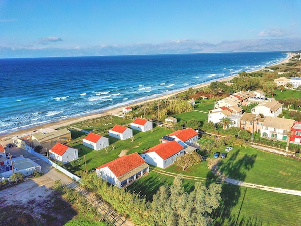An aerial view of a coastal residential area with houses, a beach, and the ocean.