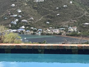 A coastal view with houses on a hillside, a swimming pool in the foreground, and boats on the water. - BLUE KAI, Water View, 2 King Suites Outdoor Native Stone Showers (St John)