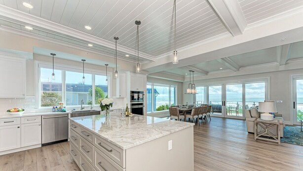 A spacious kitchen with a large island, modern appliances, and large windows offering ocean views. - Buena Vista #2: Luxury Beach Front Condo, Amazing Views, Pool by Anna Maria Life Vacation Rentals (Holmes Beach)