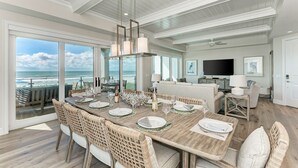 A spacious dining area with a view of the ocean, a cozy living area with a flat-screen TV, and a modern kitchen. - Buena Vista #2: Luxury Beach Front Condo, Amazing Views, Pool by Anna Maria Life Vacation Rentals (Holmes Beach)