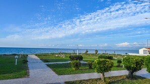 Un paseo marítimo con sendero pavimentado, césped y pequeños árboles.