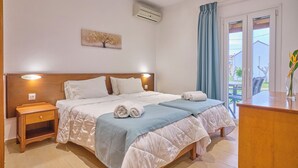 Habitación de hotel con cama, mesita de noche, aire acondicionado, ventana con cortinas y vista al exterior.