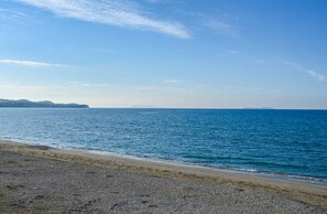 Une plage d’où l’on a une vue dégagée sur la mer et sur les reliefs lointains.