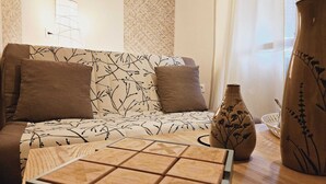 A living room with a patterned sofa, a wooden coffee table, and decorative vases. - *** Family Room Au petit bonheur (Gramat)