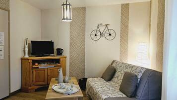 Een gezellige woonkamer met een houten tv-meubel, een bank en een fietsdecoratie.