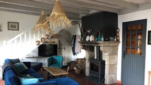 A cozy living room with a blue sofa, a wooden coffee table, and a fireplace. - Sea view house (56780 - ILE AUX MOINES)