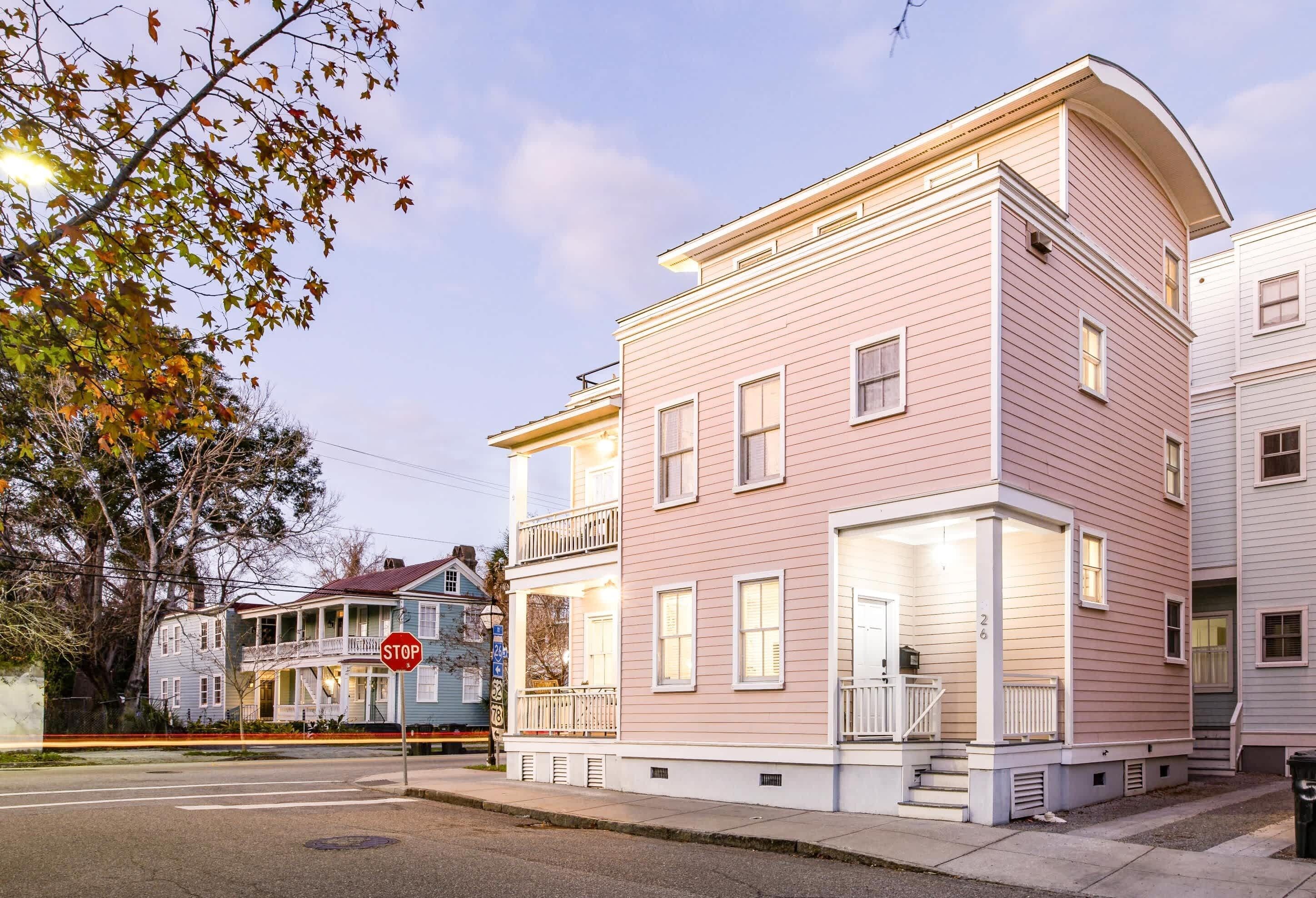 En rosa, flerlagsbygning med balkon, et stopskilt og et gadesyn.