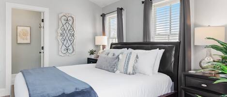 A bedroom with a bed, bedside tables, a nightstand, and a window with curtains.