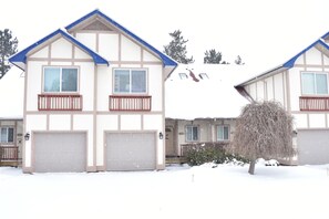 A two-story residential building with a gabled roof, a front garage, and a small porch.