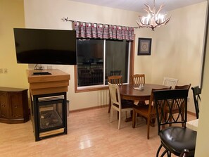 A dining area with a wooden table and chairs, a television on a stand, and a fireplace.