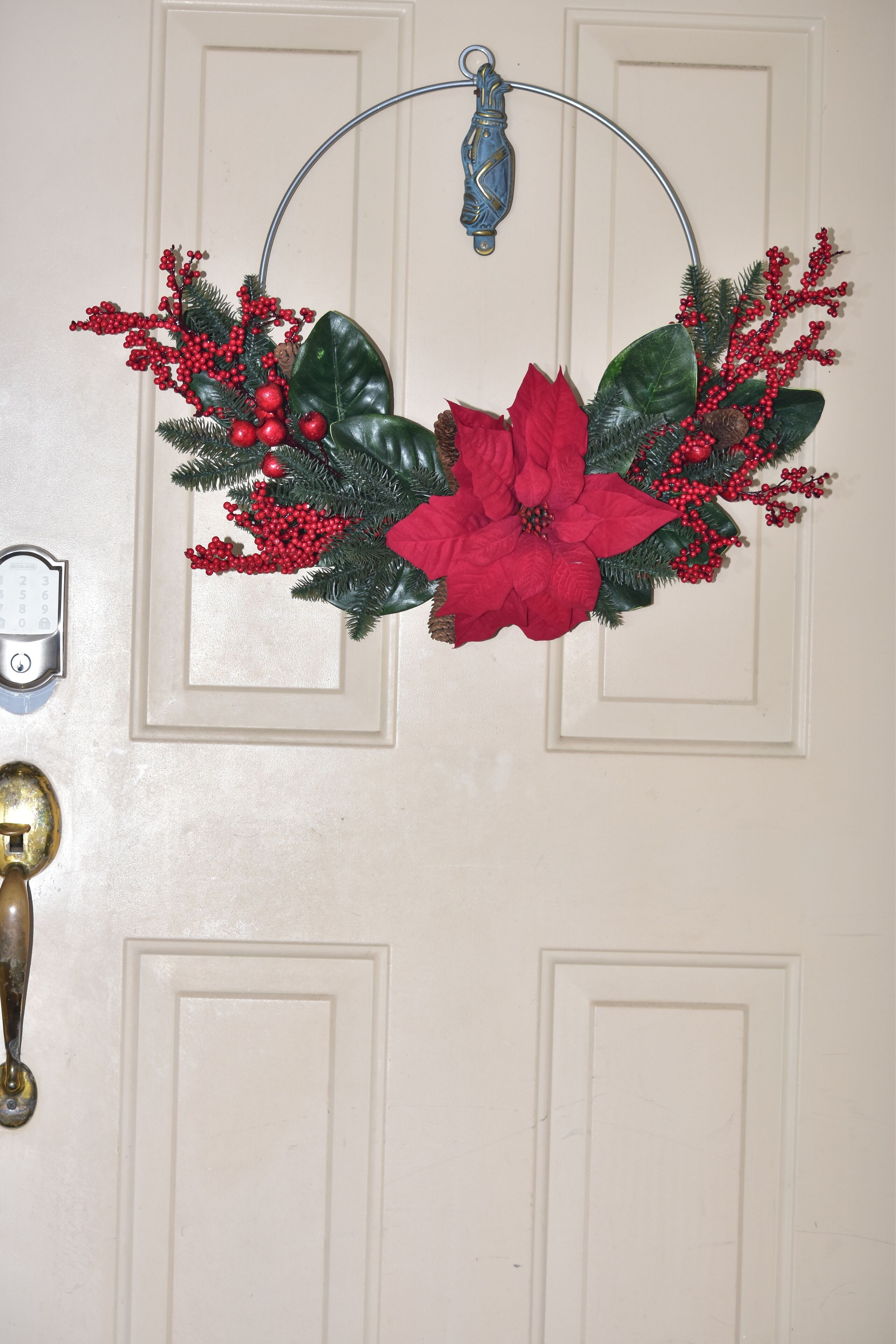 A white door with a decorative wreath and a brass doorbell.