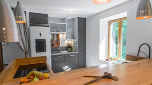 A modern kitchen with grey cabinets, a wooden island, and pendant lighting. - AN OASIS WHERE TO FIND THE ESSENTIALS<br>AND TAKE A BREAK IN CONSCIOUSNESS & IN (SAINT USUGE)
