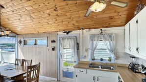 A wooden interior with a dining area, kitchen, and a view of the outside.