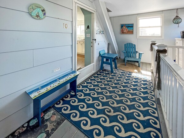 A hallway with a blue and white patterned floor, a blue bench, and a door leading to a room.