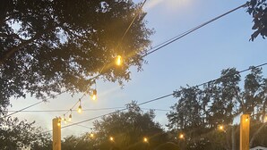 An outdoor patio area with a fire feature in the center, surrounded by stone walls and a paved floor. - Private House w/ HEATED Pool and 4 Passes to the Daytona Aquarium & Rainforest! (Port Orange)