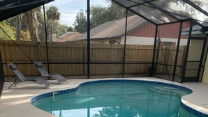 A swimming pool with a clear blue water, surrounded by a wooden fence, and equipped with metal pool ladders. - Private House w/ HEATED Pool and 4 Passes to the Daytona Aquarium & Rainforest! (Port Orange)