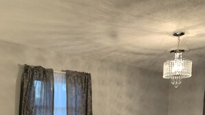 Un dormitorio con cama, cortinas y una araña.