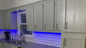 Una cocina con armarios grises claros, un lavamanos de acero inoxidable y un lavavajillas.