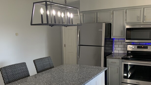 Una cocina con encimera de granito, electrodomésticos de acero inoxidable y armarios blancos.