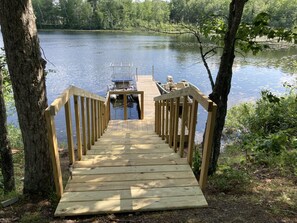 Un molo di legno che conduce a una piccola barca su un lago calmo, circondato da alberi.