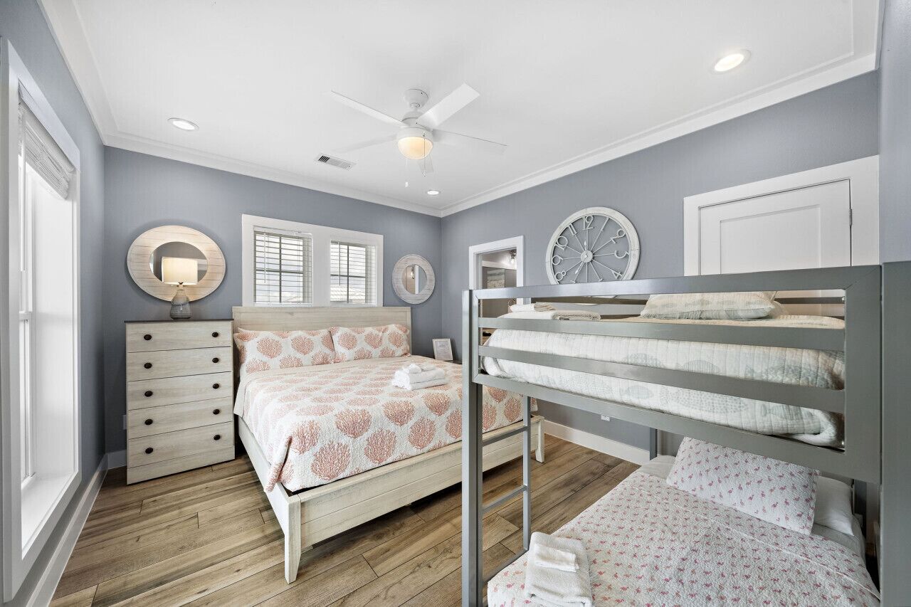 A bedroom with a bed, a dresser, a vanity, and a bunk bed.