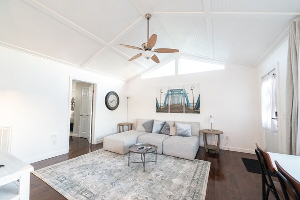 A spacious living room with a large sectional sofa, a ceiling fan, a painting of a bridge, and a dining area with a table and chairs. - WALK EVERYWHERE in North Chat! -VIEWS- 2 KING Beds (Chattanooga)