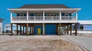 A two-story beach house with a balcony, a garage, and a clear blue sky. - OHana, Picturesque Home for Tranquil Travels (Navarre)