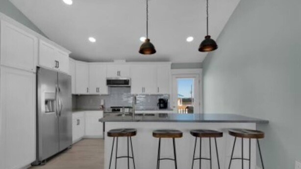 A modern kitchen with stainless steel appliances, a central island with stools, and pendant lighting. - OHana, Picturesque Home for Tranquil Travels (Navarre)