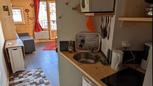 A compact kitchen with a refrigerator, microwave, and sink. There's a small countertop and a window with curtains. - Avoriaz - charming studio with balcony in the heart of the resort (Morzine)